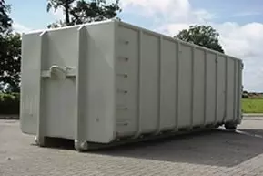 Een grote lichtgrijze gesloten container op een verhard terrein
